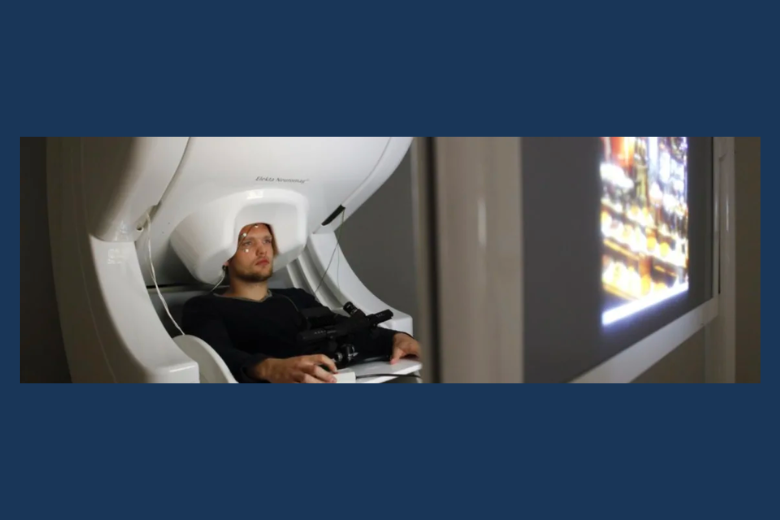 Man sitting under a white MEG machine
